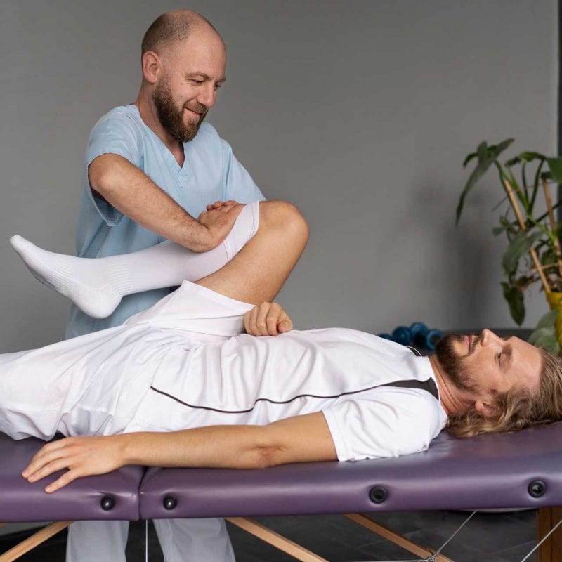 Doctor helping an athlete with his knee rehabilitation and stretching.