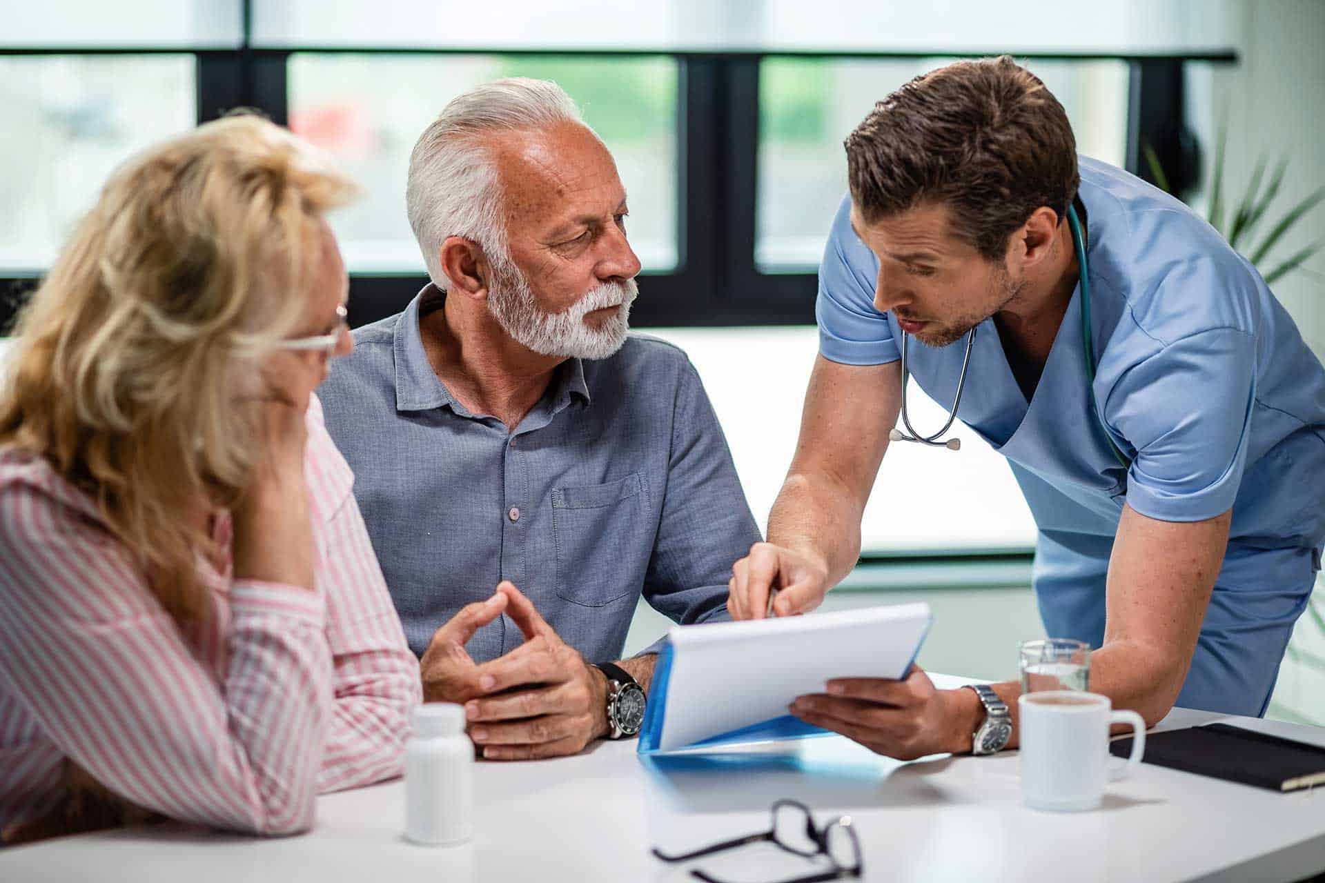 Experienced chiropractor discussing treatment options with senior patients in a modern office setting.