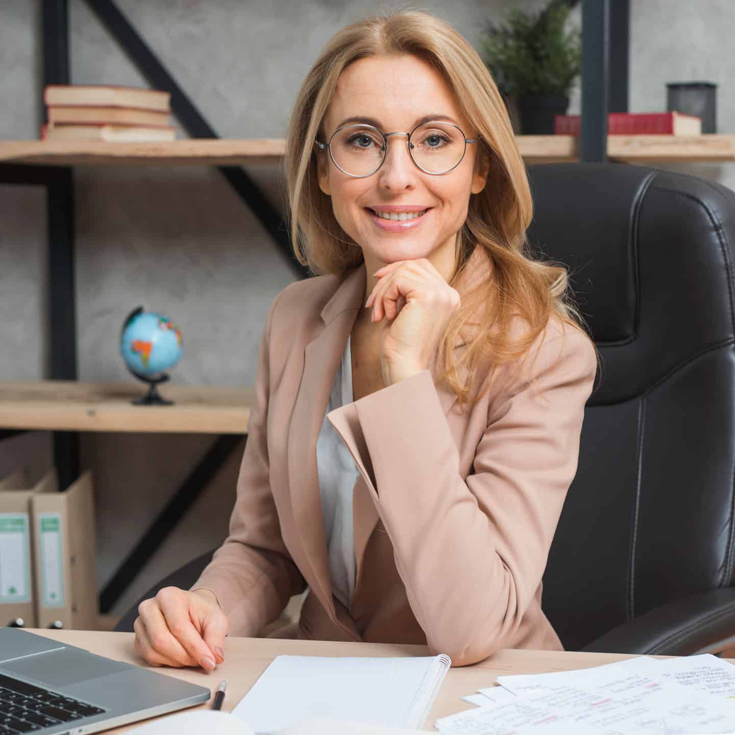 Friendly woman with glasses at her desk, representing premier chiropractic services in Eatontown.